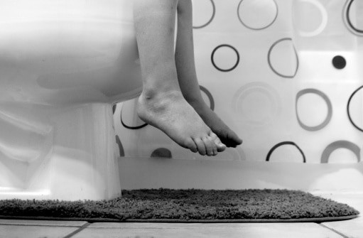 Child's feet dangling off toilet