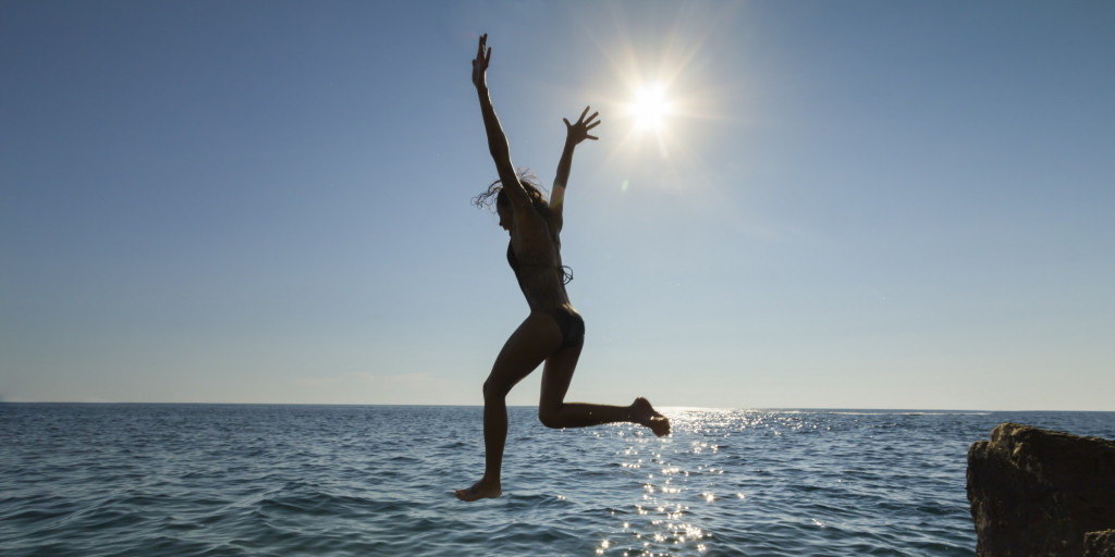 Woman Jumping into Ocean